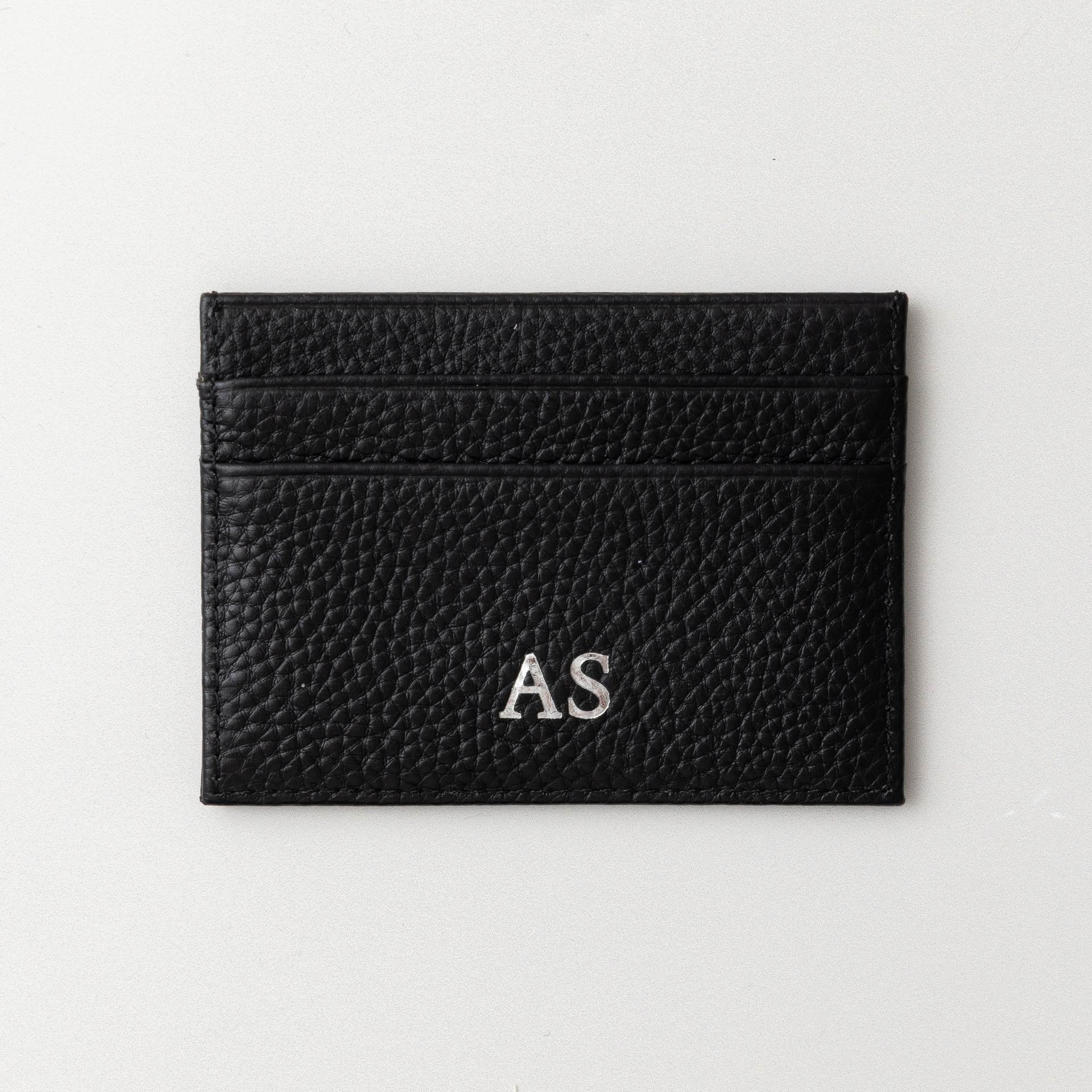 A black genuine leather card holder with a sleek, smooth finish.