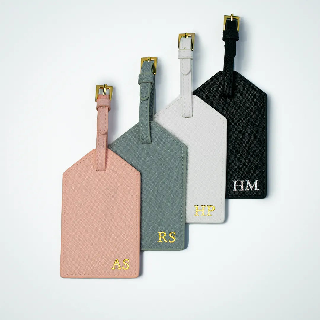 Personalized leather luggage tag in four colors: black, white, pink, and gray. Customizable with your logo or name for a unique, stylish, and durable travel accessory.